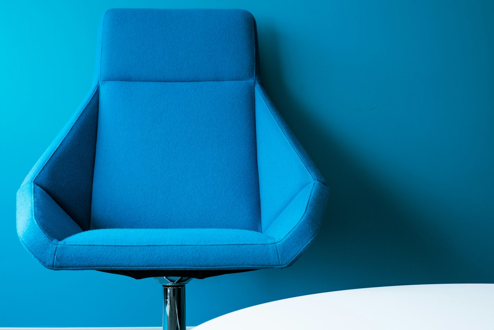 A designer lounge chair against a blue wall